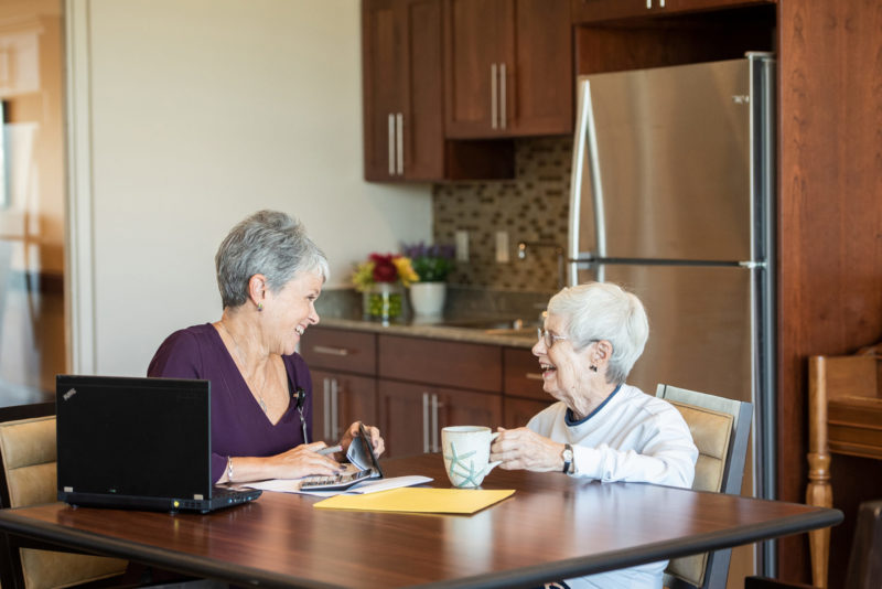 two seniors talking at kitchen table