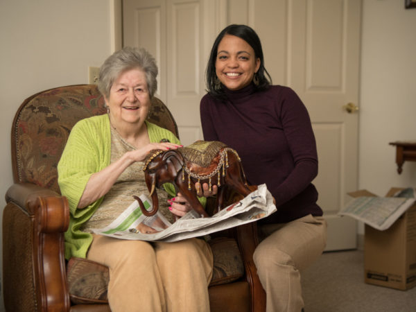 Two women holding decorative wooden elephant