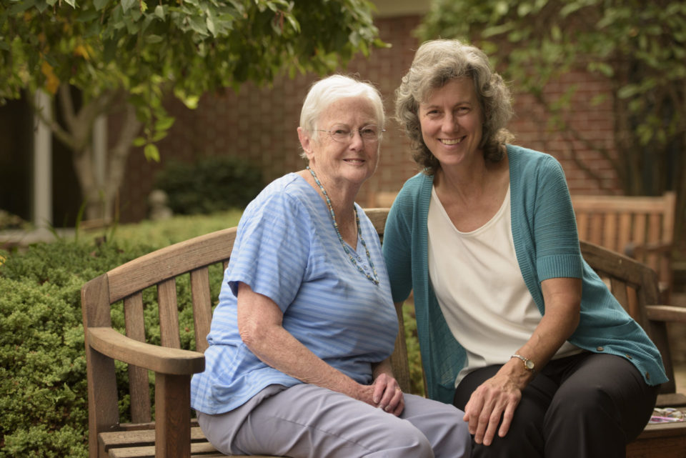 resident and caregiver on outdoor bench